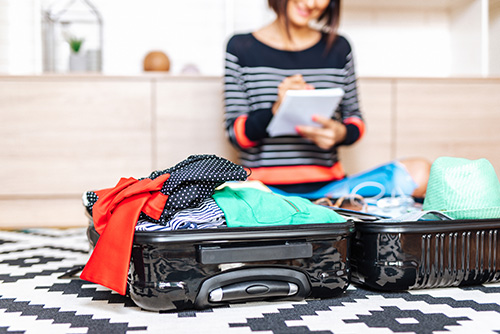 Young Woman With Checklist Packing Suitcase